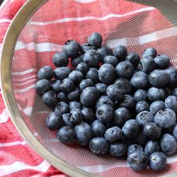 washed blueberries in fine mesh strainer on red cloth