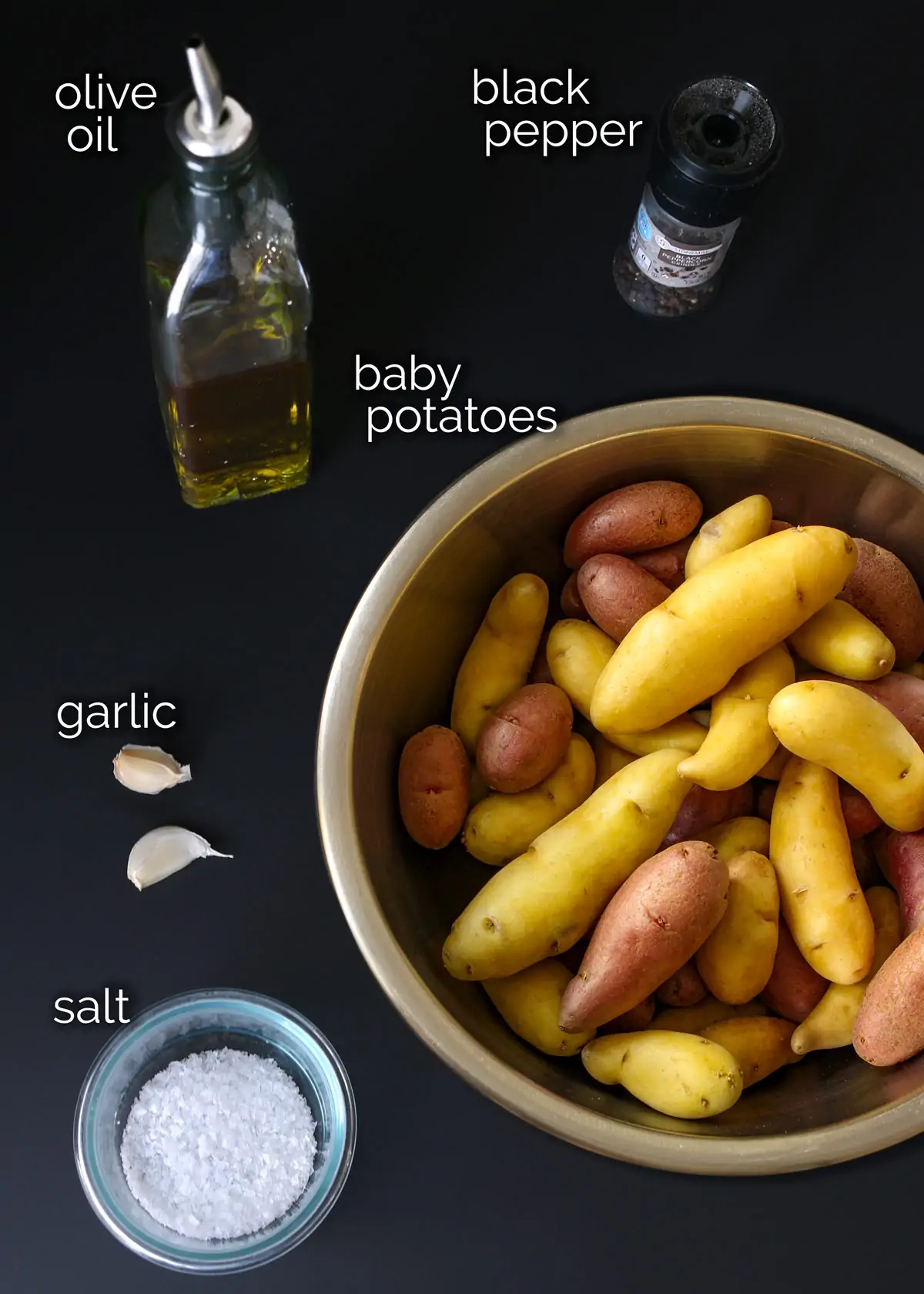 ingredients for making slow cooker potatoes laid out on black counter.
