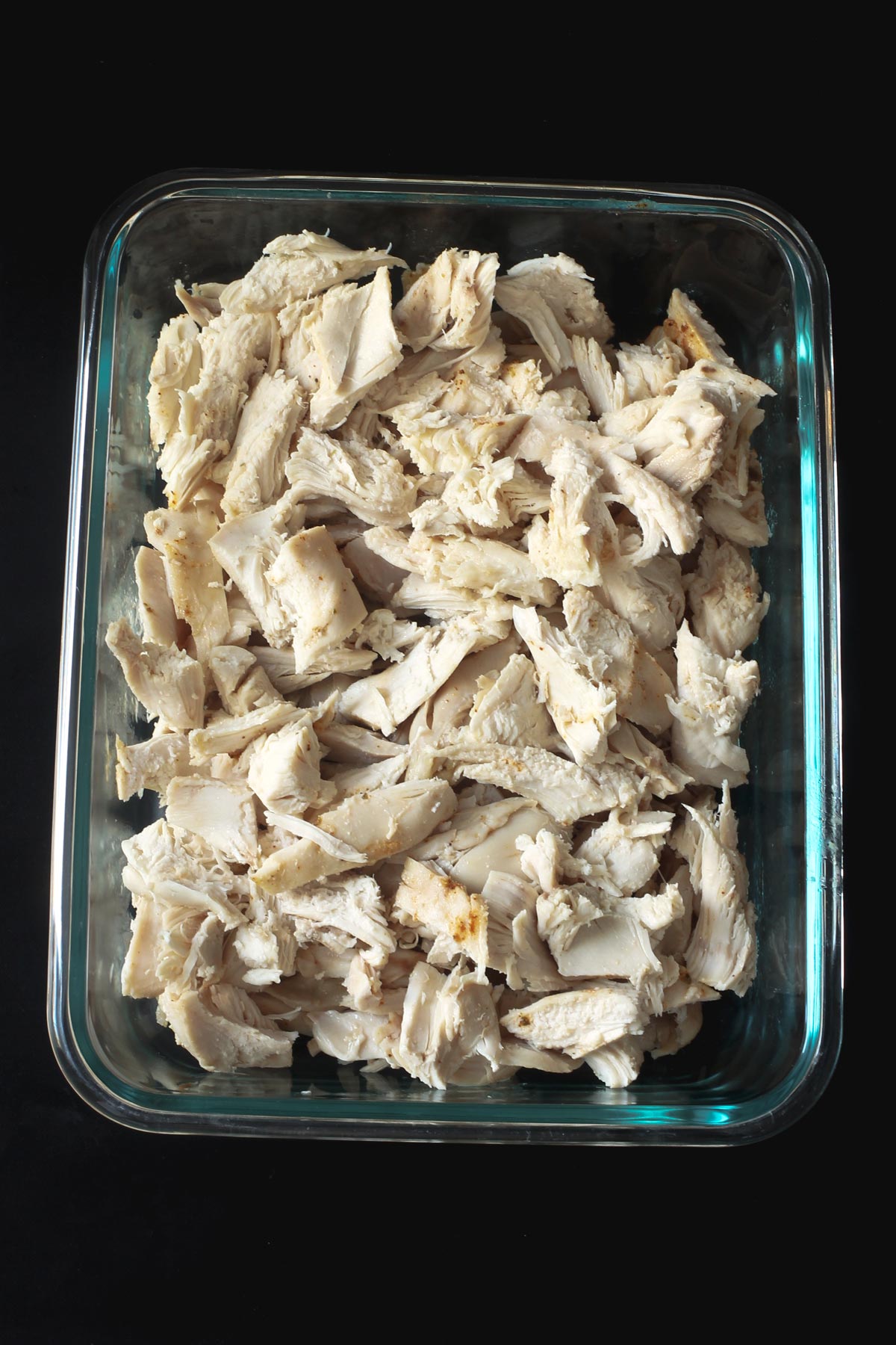 glass dish with cubed chicken cooked in the slow cooker ready for recipes.