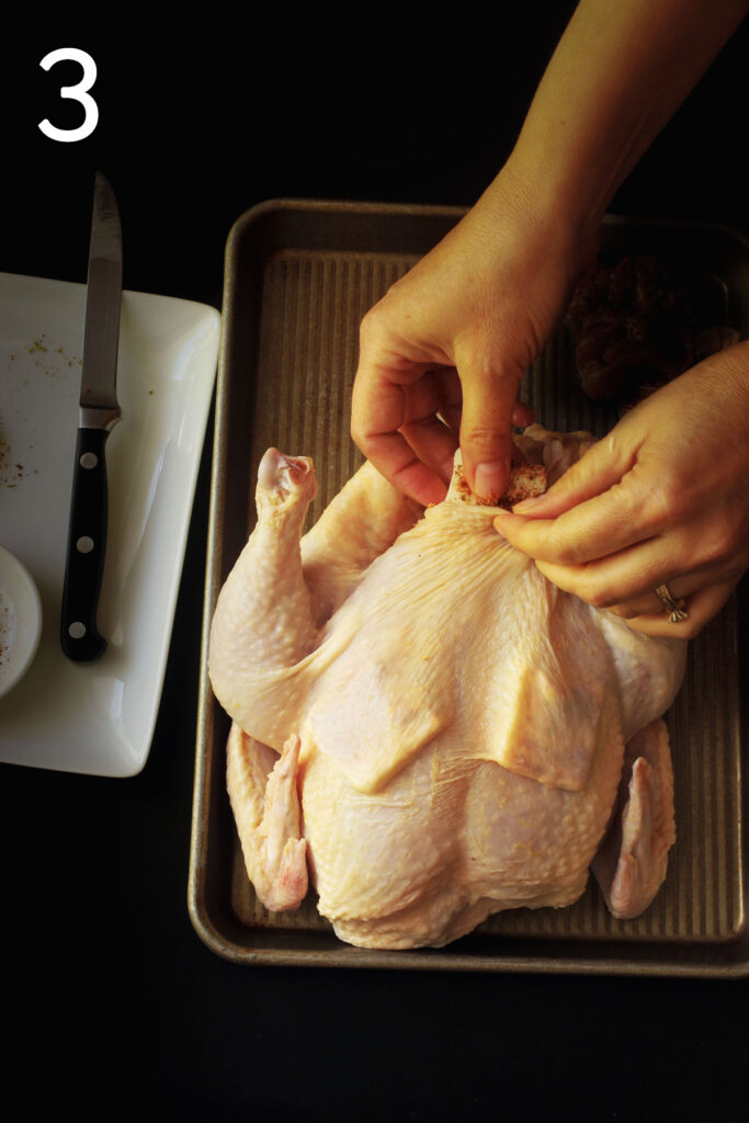 hand sliding butter pats under the skin of the chicken.