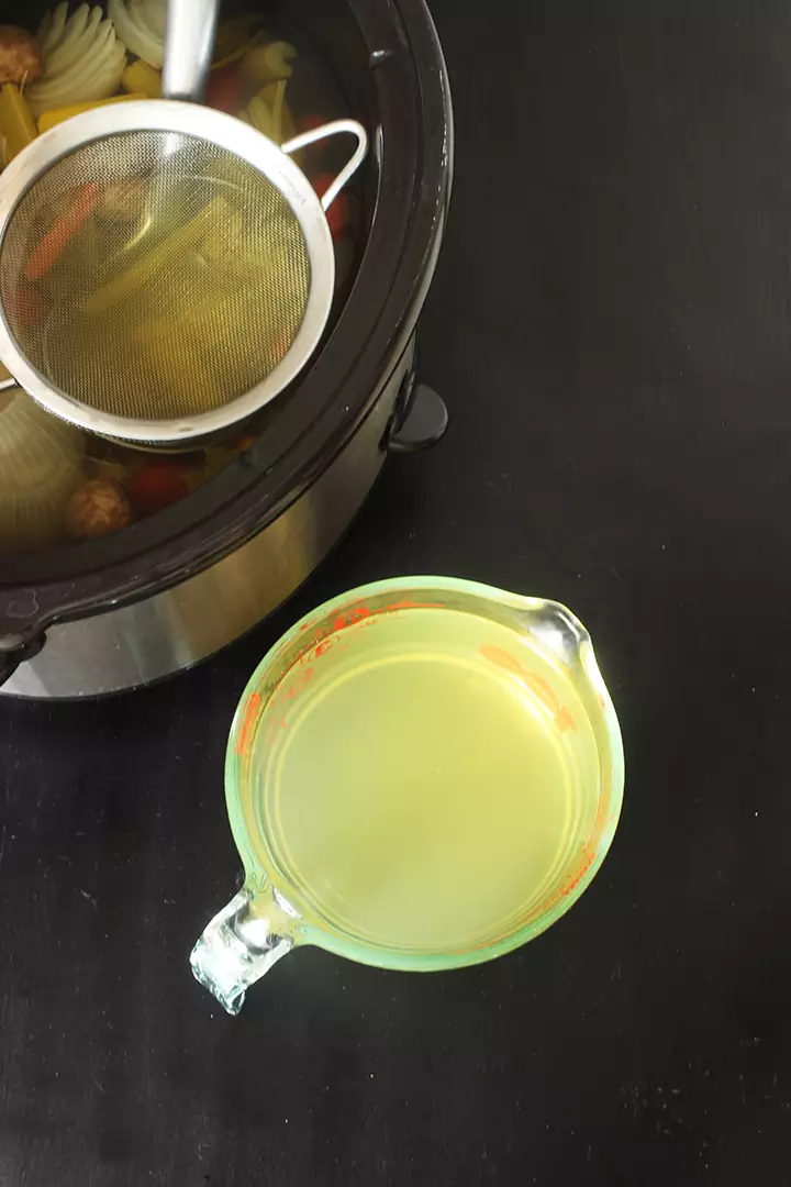 strained vegetable broth in glass measure