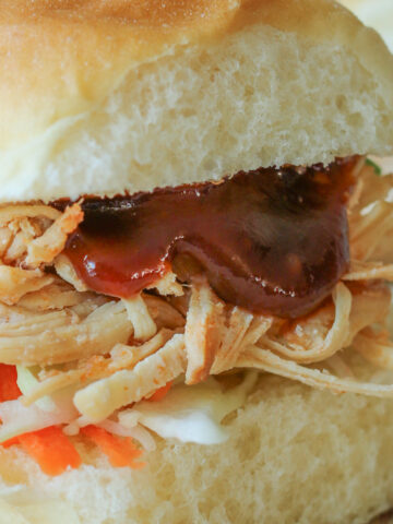 closeup of sweet and sour pulled chicken on hawaiian bun.