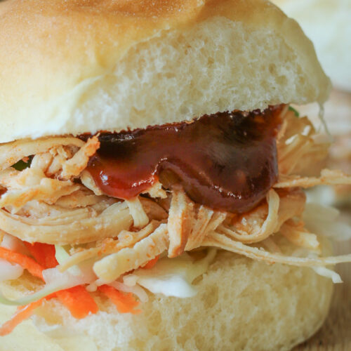 closeup of sweet and sour pulled chicken on hawaiian bun.
