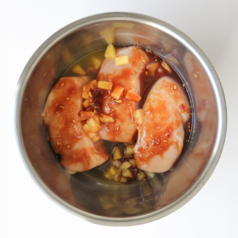 chicken breasts and sauce in pressure cooker insert.