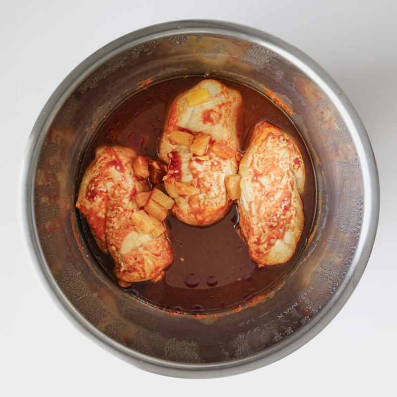 cooked chicken and sauce in metal insert.