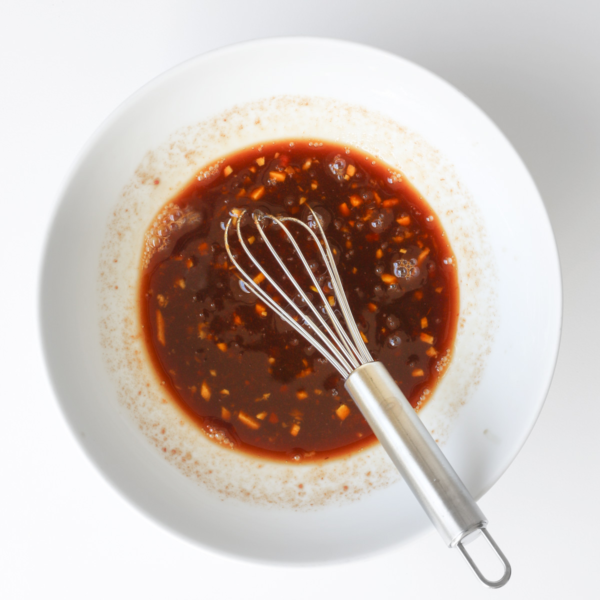 sweet and sour marinade in a bowl with a whisk.