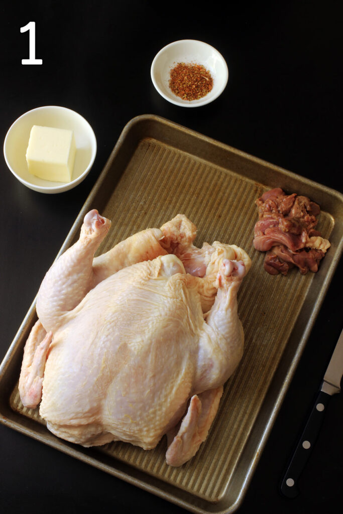 whole chicken on tray with giblets in the corner of the tray.