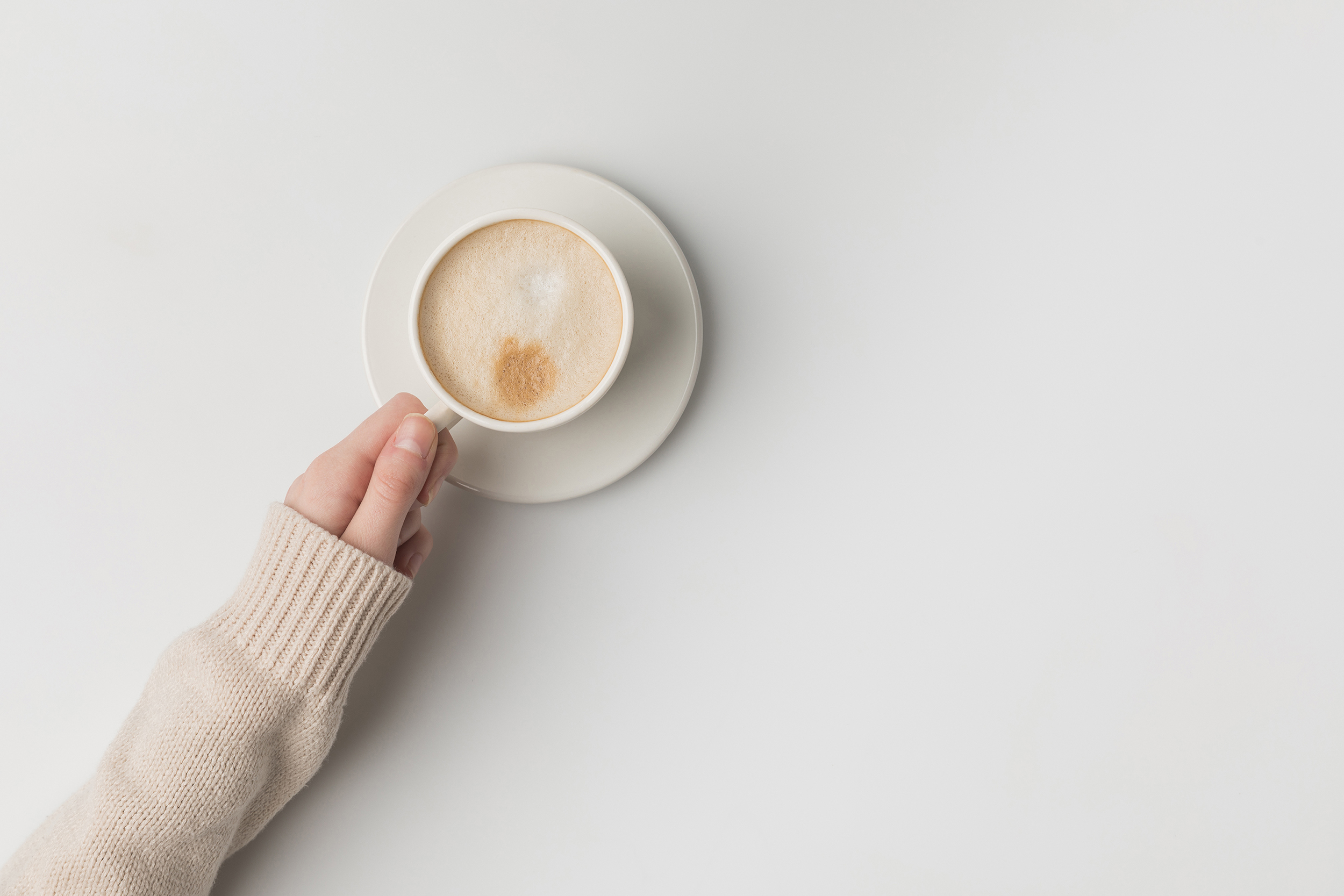 A close up of a hand holding a capuccino