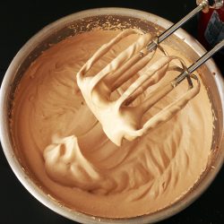 chocolate whipped cream almost fully whipped in metal bowl with beaters
