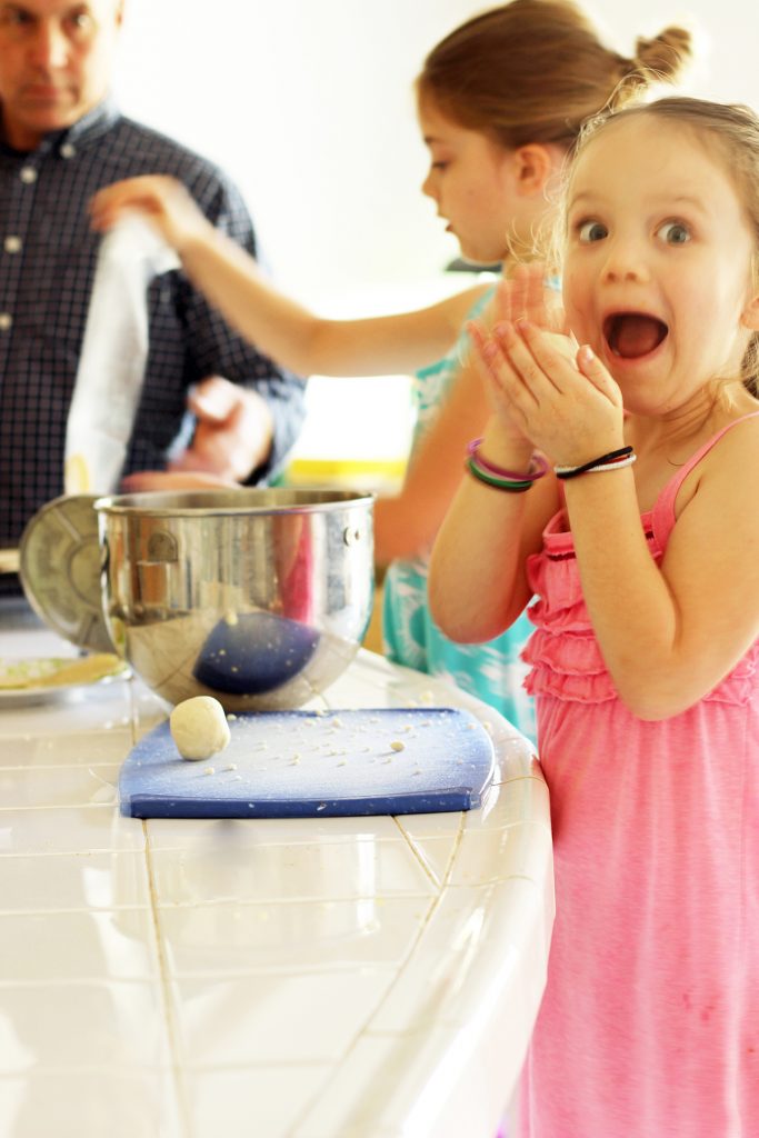 excited girl rolling balls of dough for tortillas