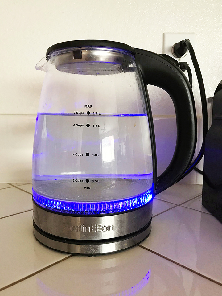 glass water kettle turned on with blue light