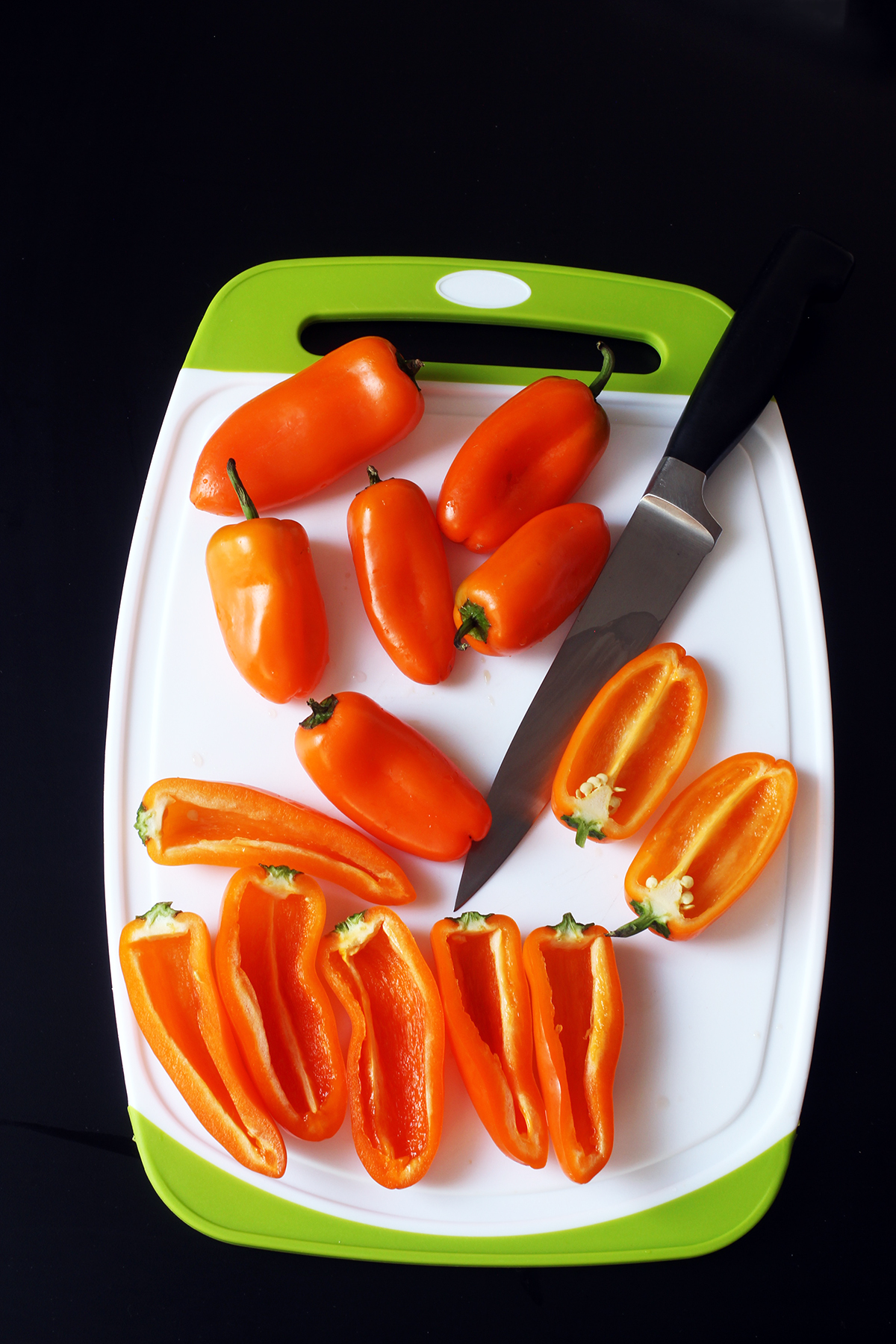 mini peppers on green and white cutting board with knife