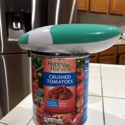 A close up of a can and electric can opener on the counter