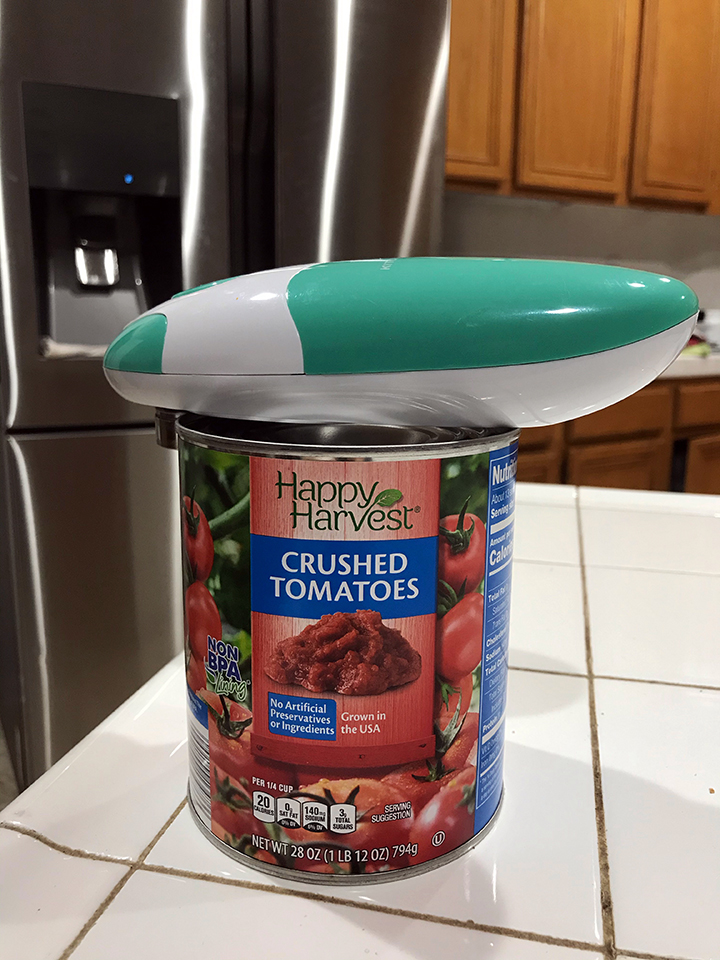 A close up of a can and electric can opener on the counter