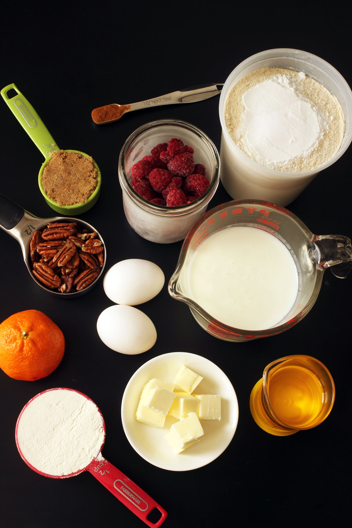 baking ingredients in measuring cups laid out on a black table top.