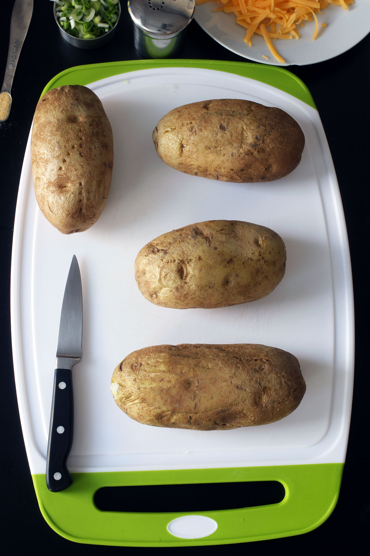 baked potatoes on board with knife