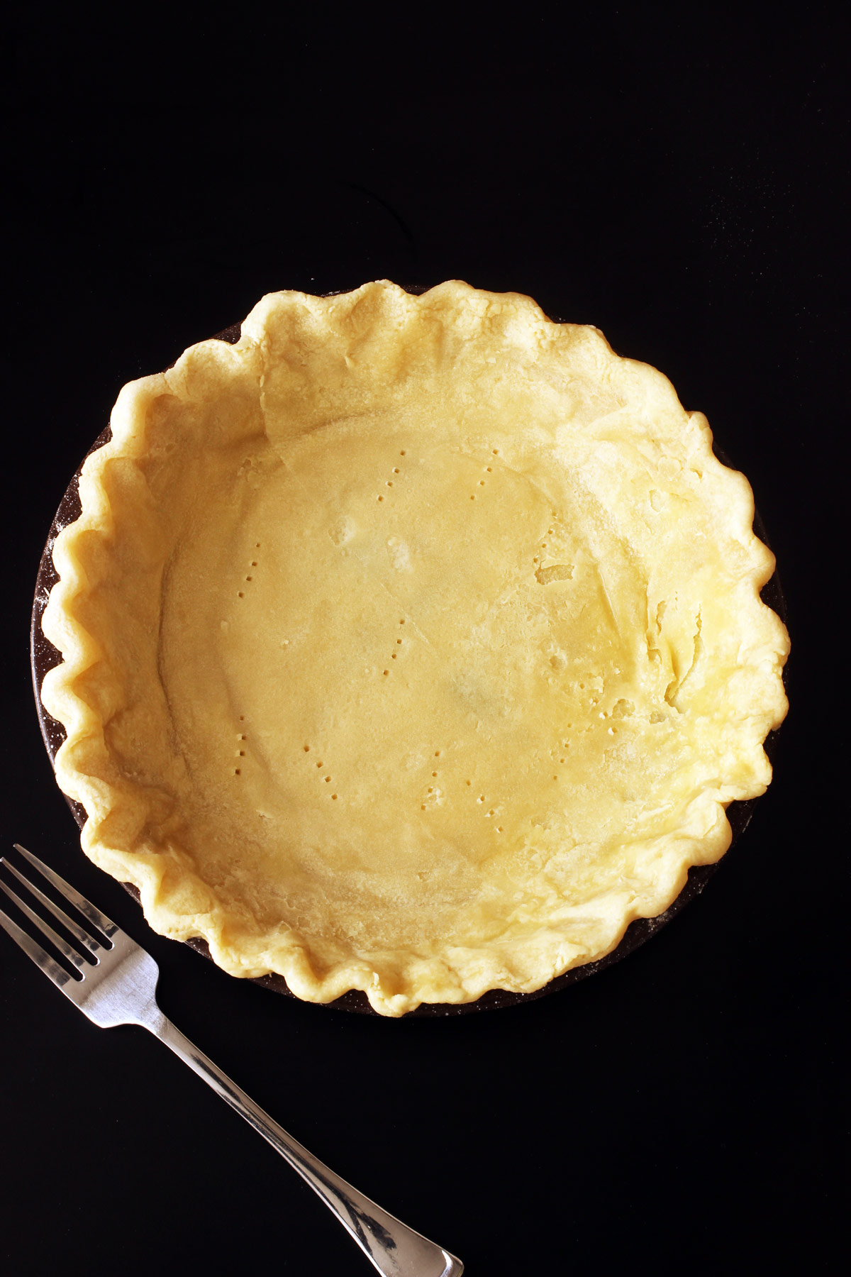 half baked pie crust with fork.