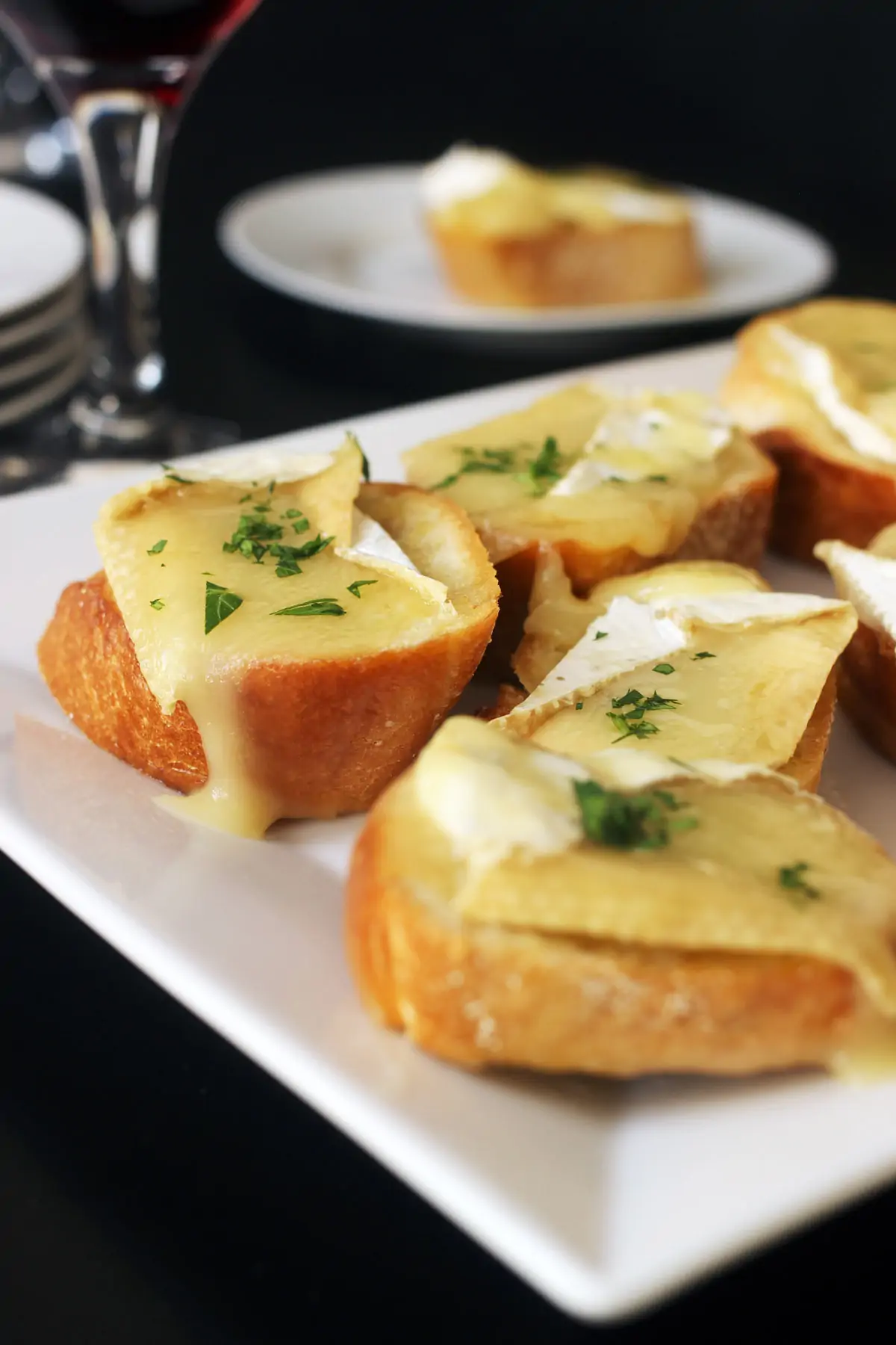 platter of brie toasts on table with wine glasses