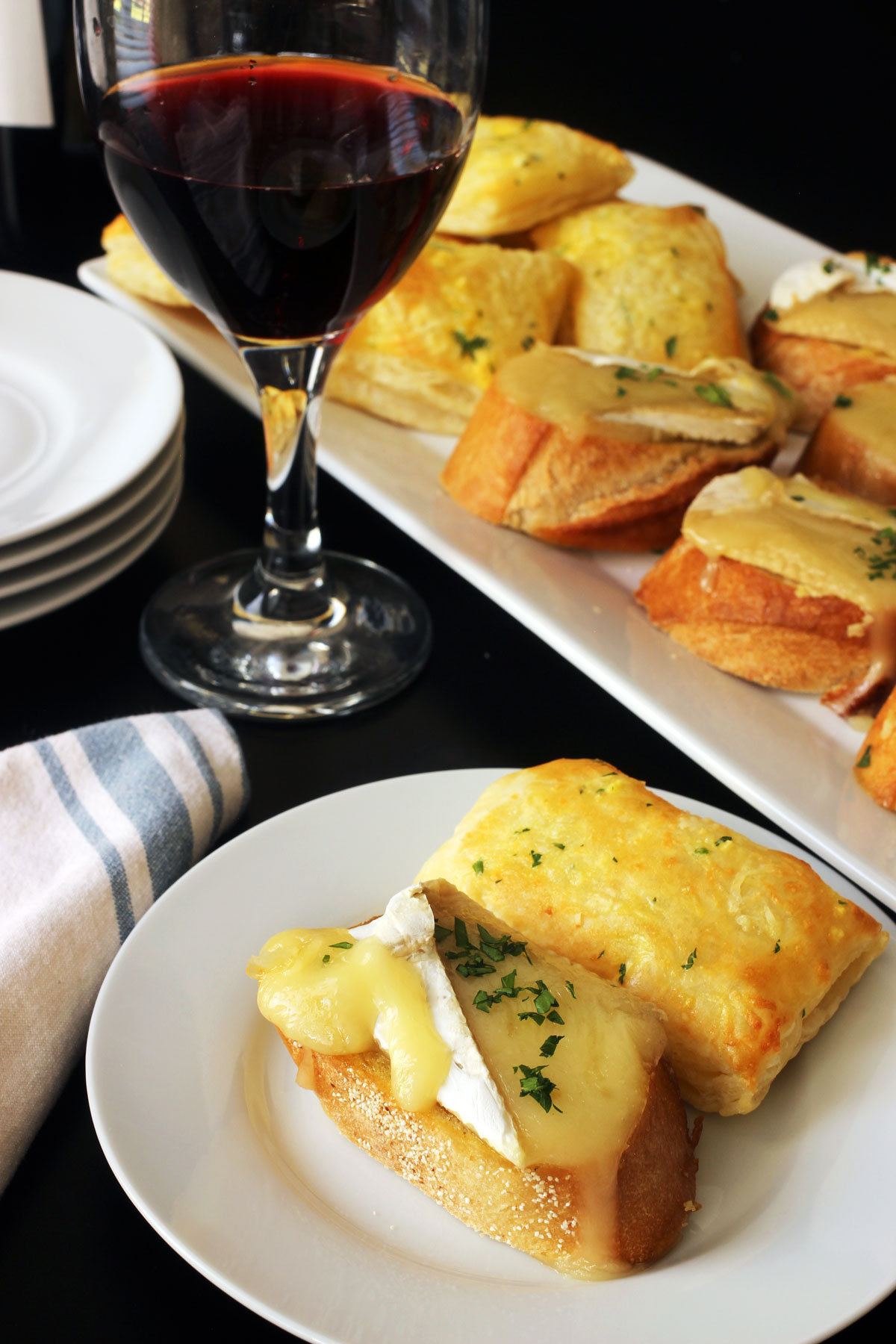 brie toast and cheese puff on plate with glass of wine