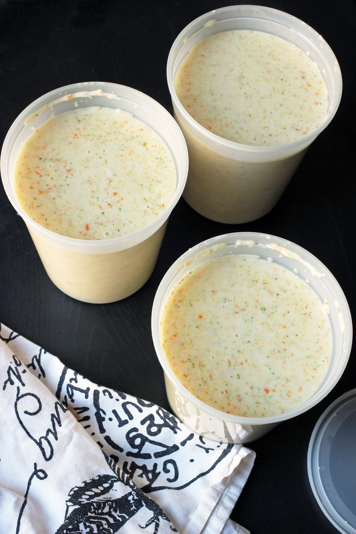 broccoli soup in freezer containers on black table.