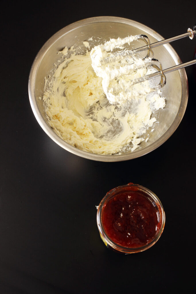 strawberry jam next to bowl of cream cheese