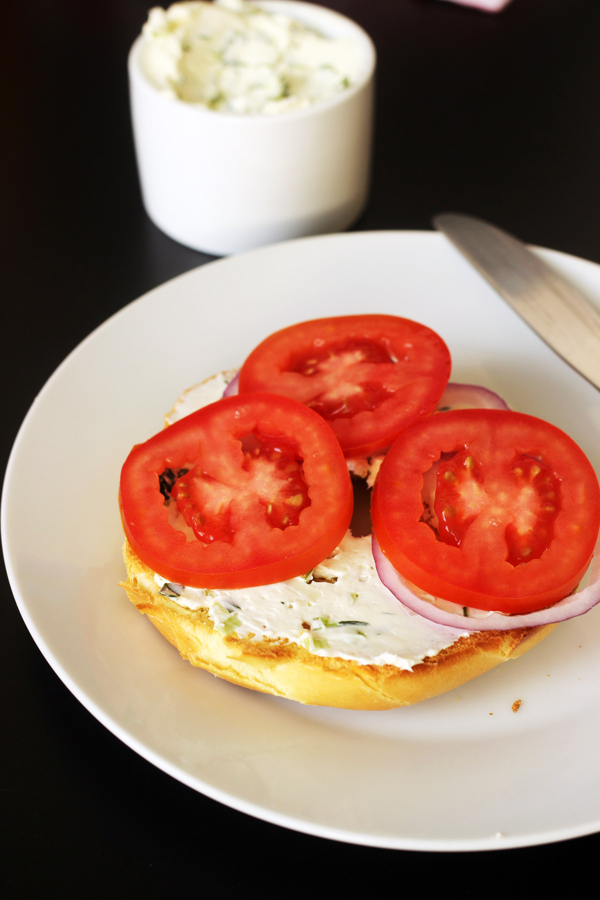 sliced tomatoes on green onion cream cheese bagel
