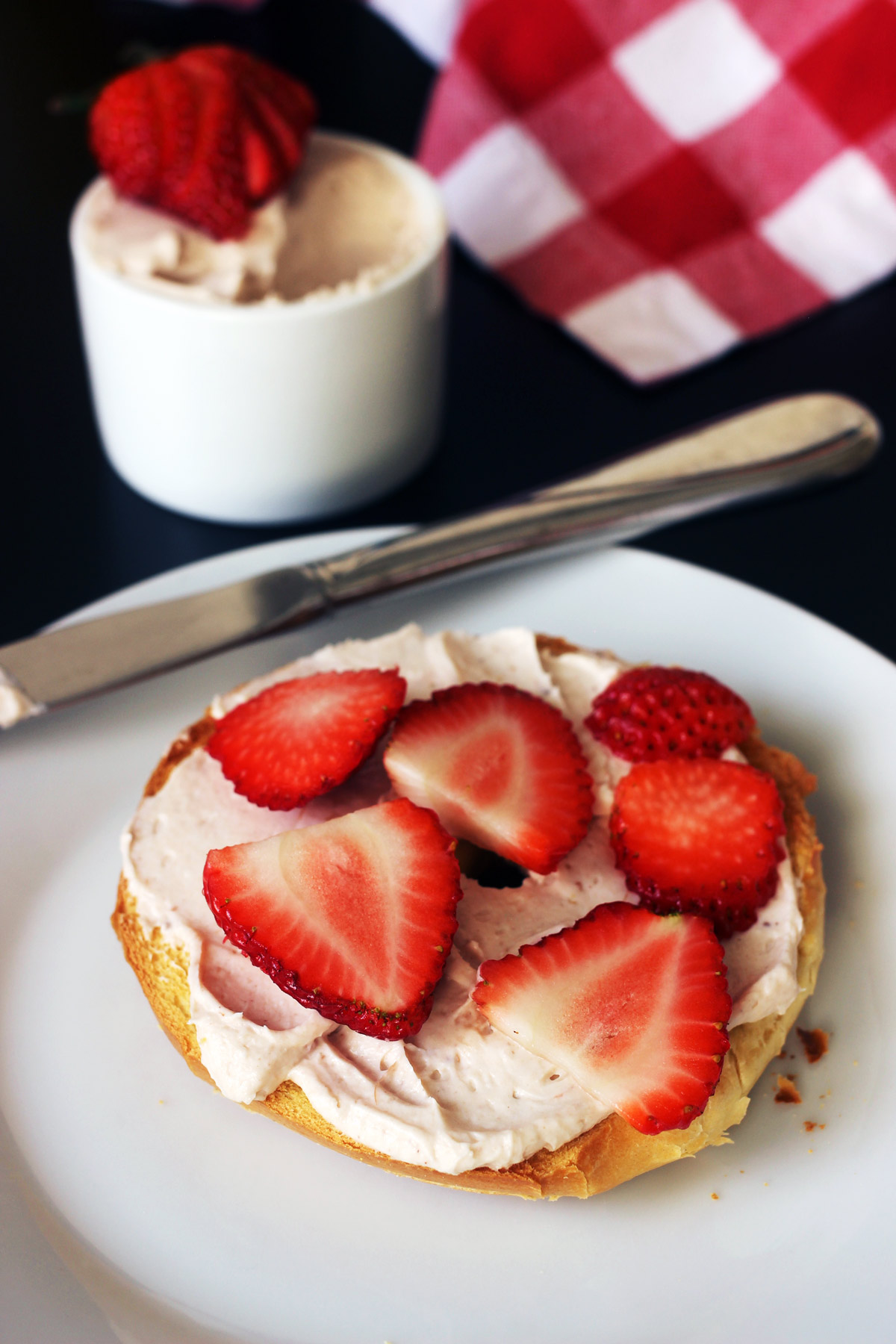 sliced strawberries on strawberry cream cheese bagel.