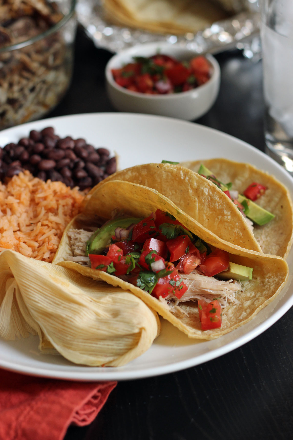 plate of pulled pork tacos, a tamale, and rice and beans. 