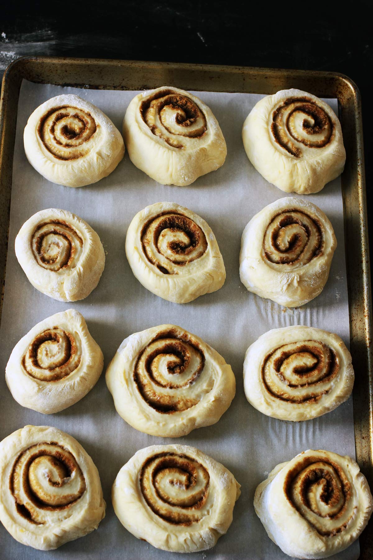 orange rolls rising on parchment-lined pan