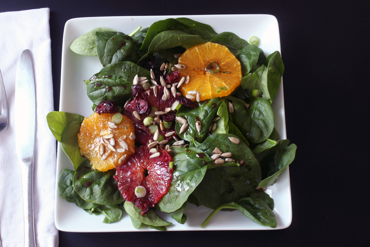 spinach salad on square plate with knife and fork