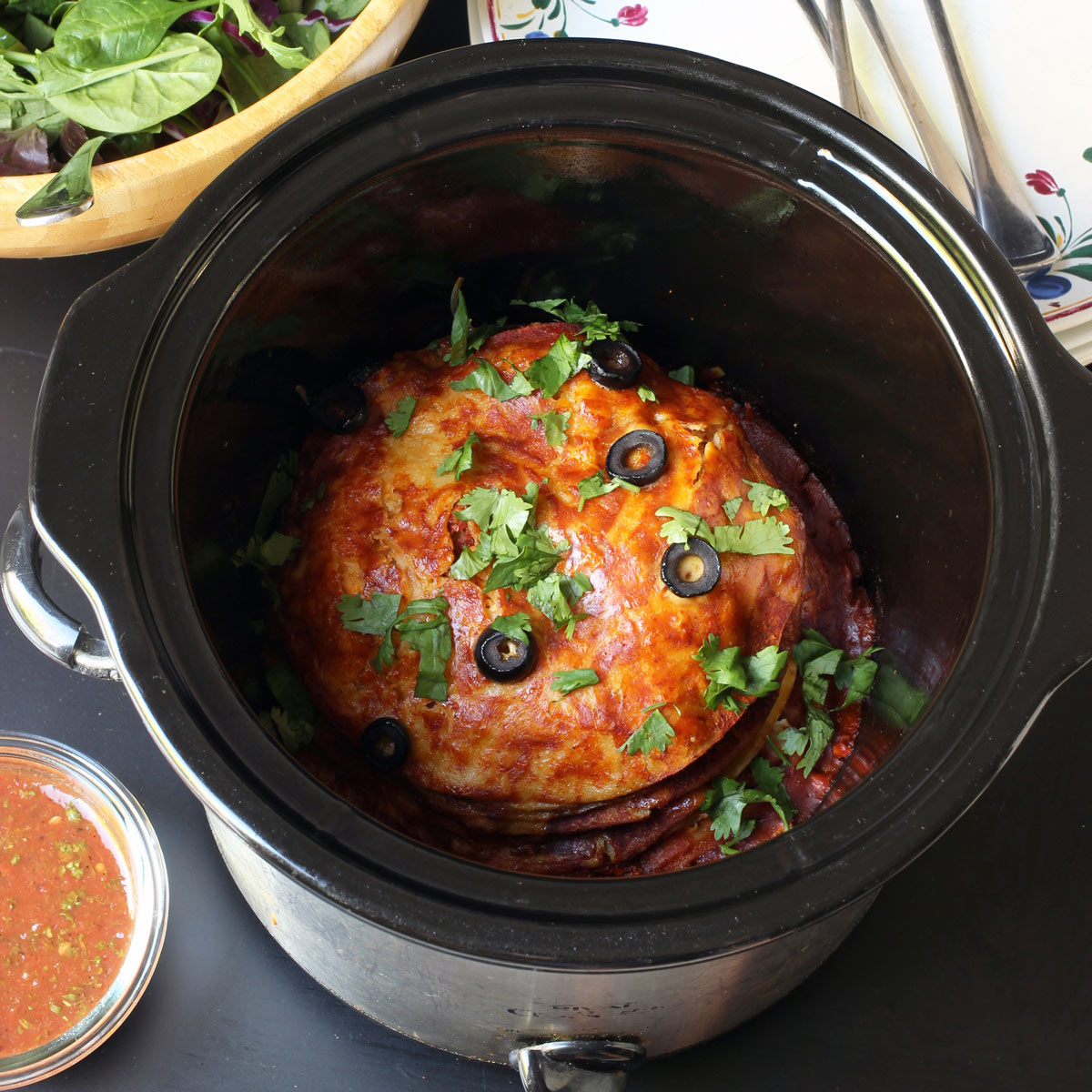 stacked red enchiladas in a round slow cooker