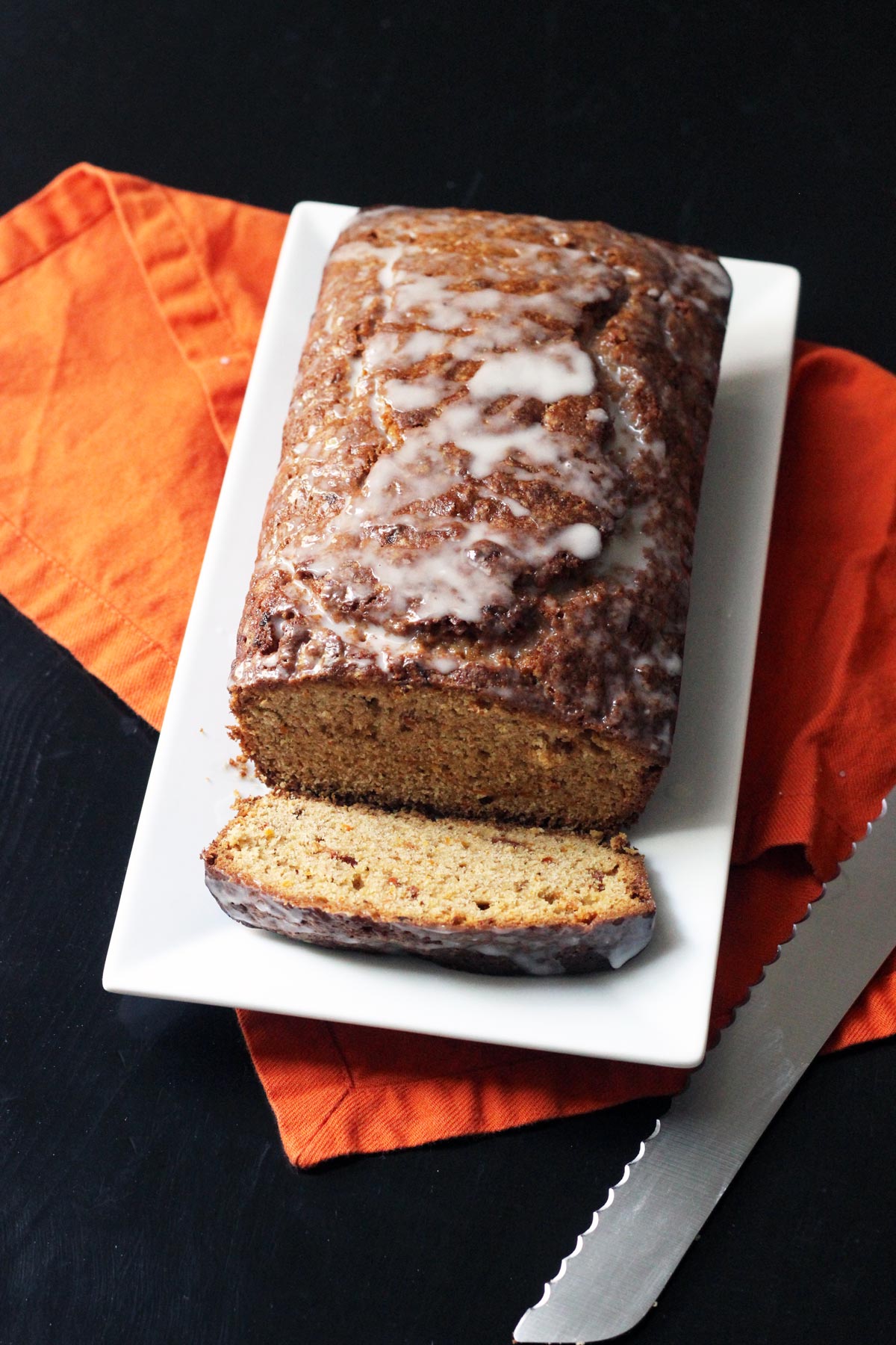 loaf of carrot bread and one slice on platter with orange napkin