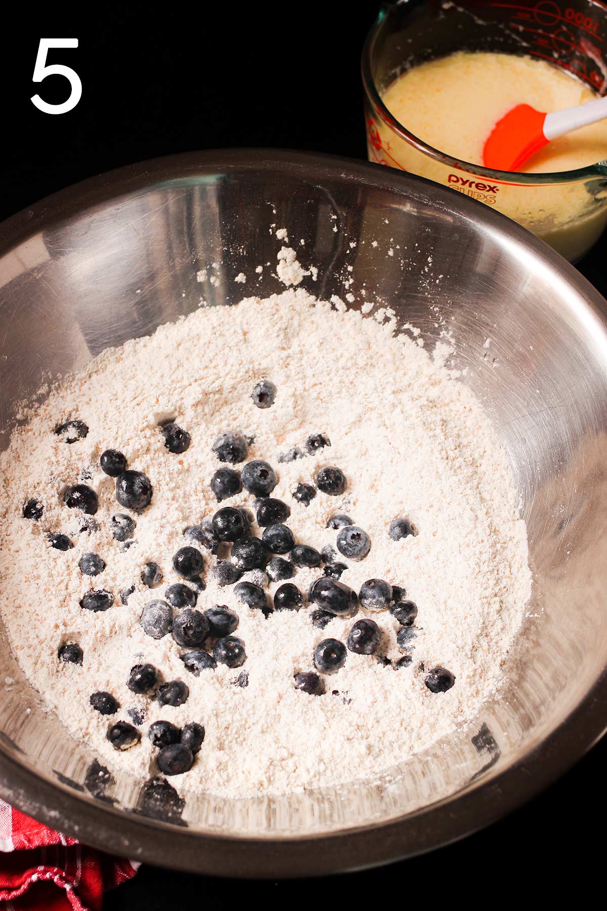 tossing blueberries into dry mixture in mixing bowl.