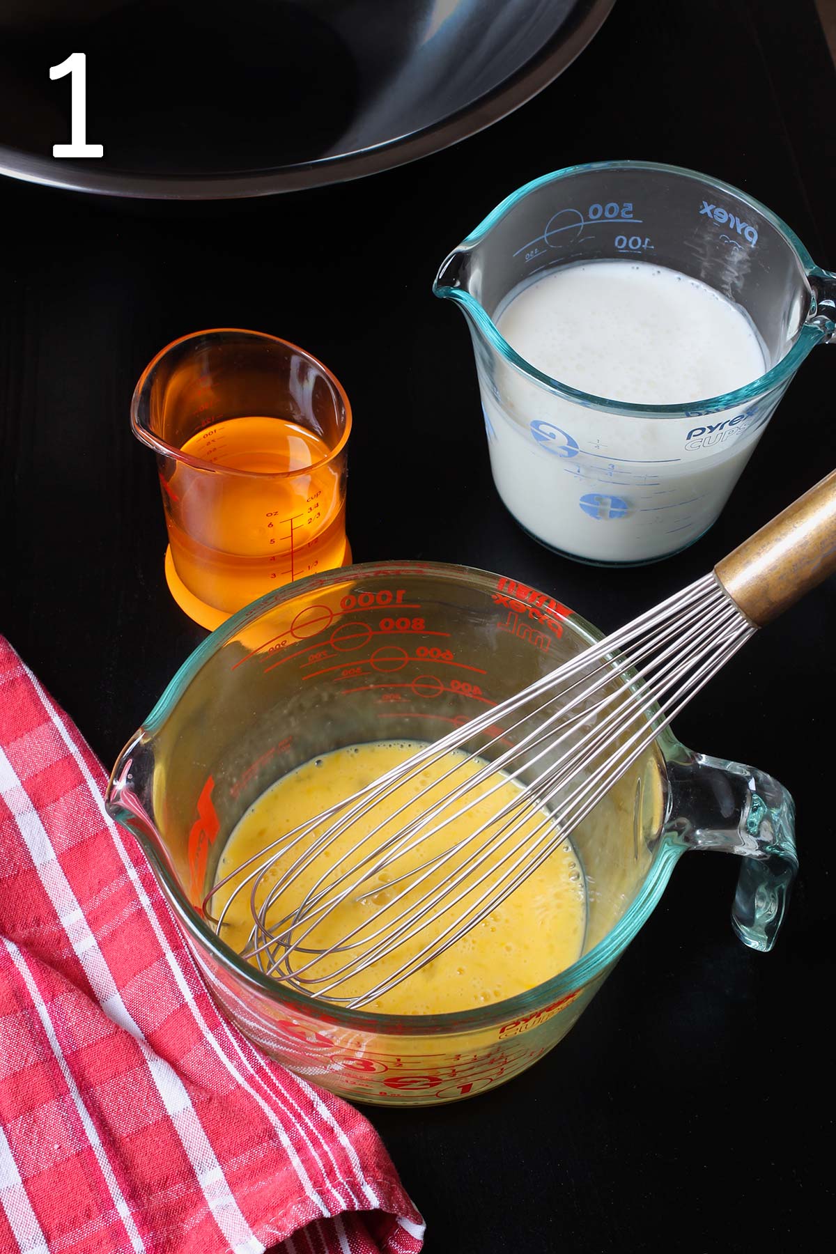 measures of oil, buttermilk, and beaten egg on the table with a red cloth.