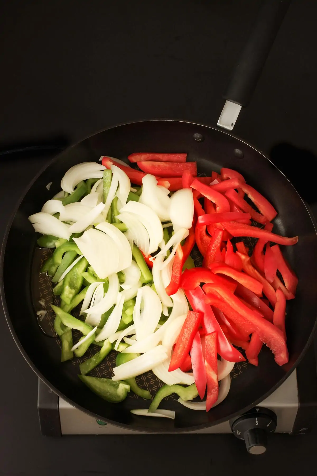 adding the peppers and onions to the oil in the hot skillet.