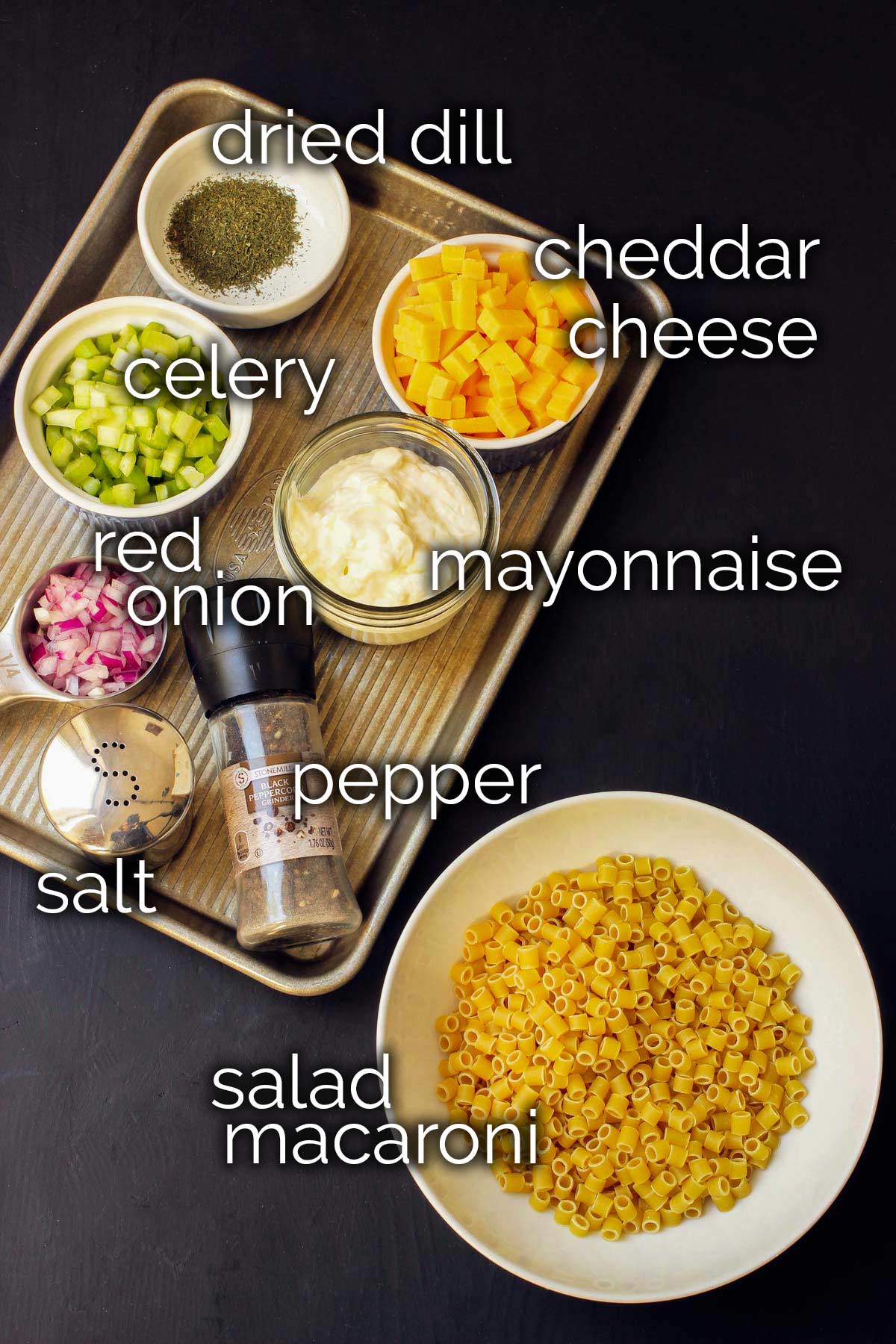 ingredients for macaroni salad laid out on black table.