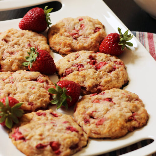 white rectangular platter holding six strawberry oatcakes with fresh strawberries next to them.