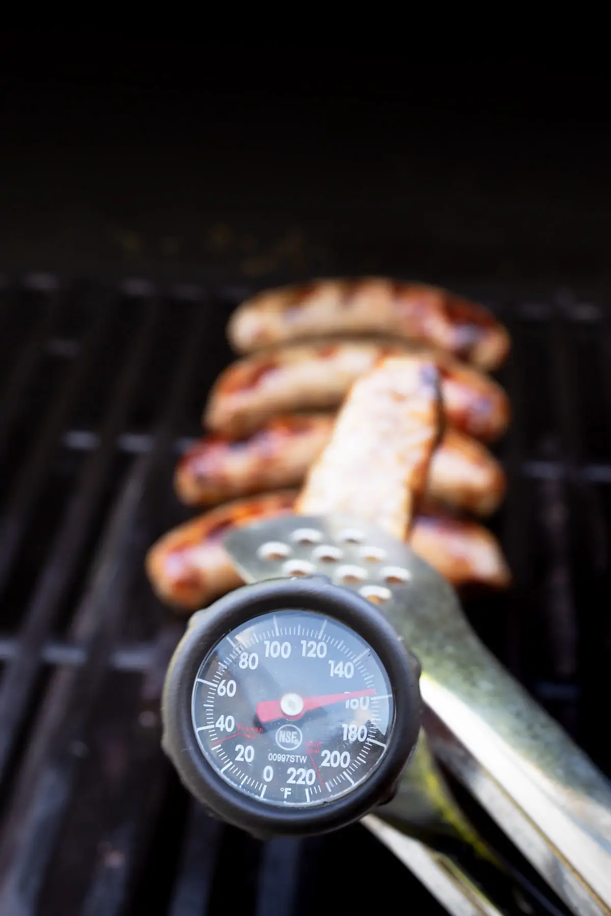 meat thermometer inserted into a brat, approaching 160 degrees.