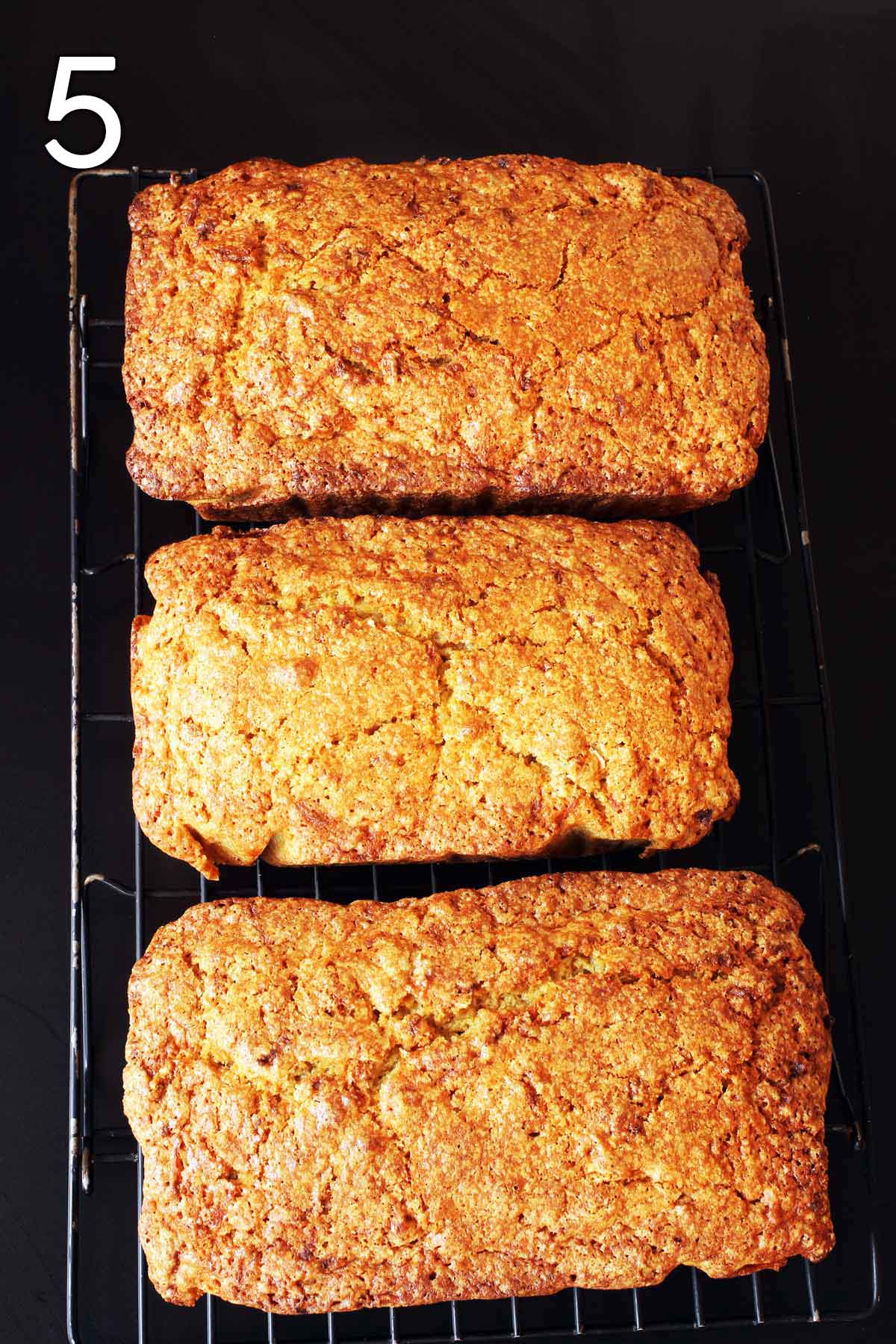 three loaves of carrot bread cooling on a wire rack.