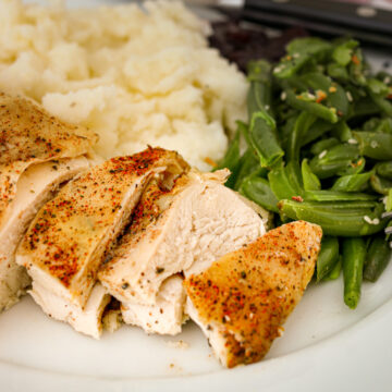 chicken breast sliced on a plate with side dishes.