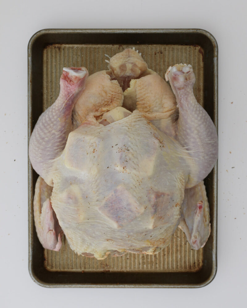 chicken on tray with pats of butter under the skin.