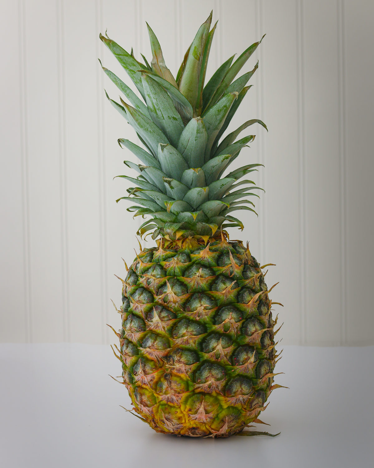 pineapple on a white table with a white beadboard background.