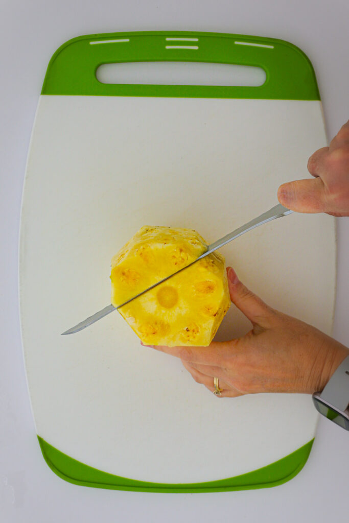 cutting through the pineapple, around the core.