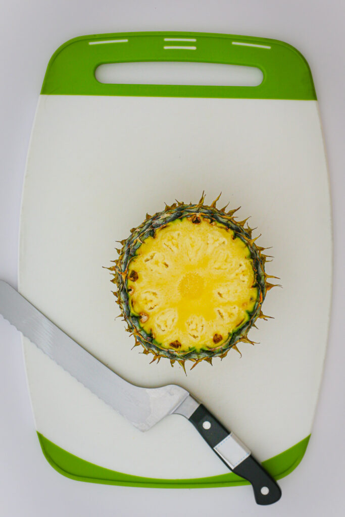 pineapple standing upright on the cutting board.