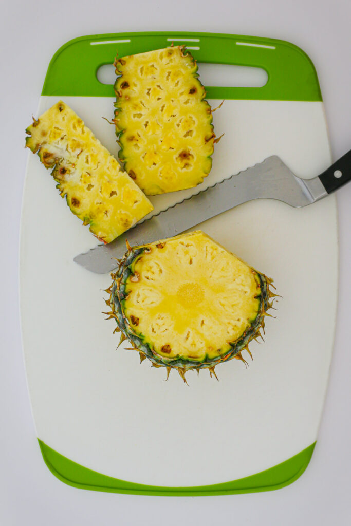 cutting away the skin from the pineapple in sections.