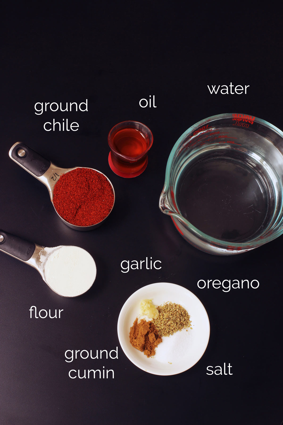 measuring cups of enchilada sauce ingredients with spices in a small white bowl.
