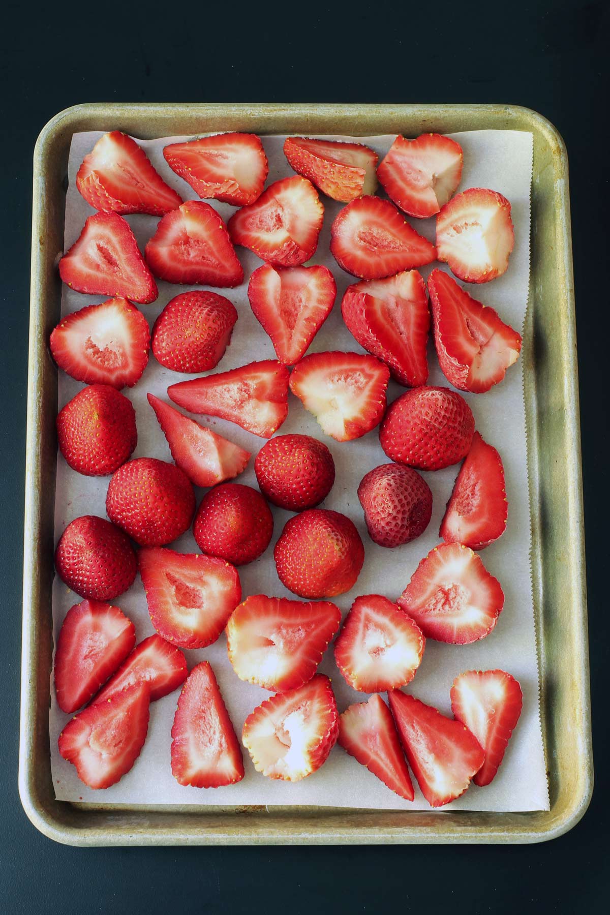 frozen strawberries on lined sheet pan.