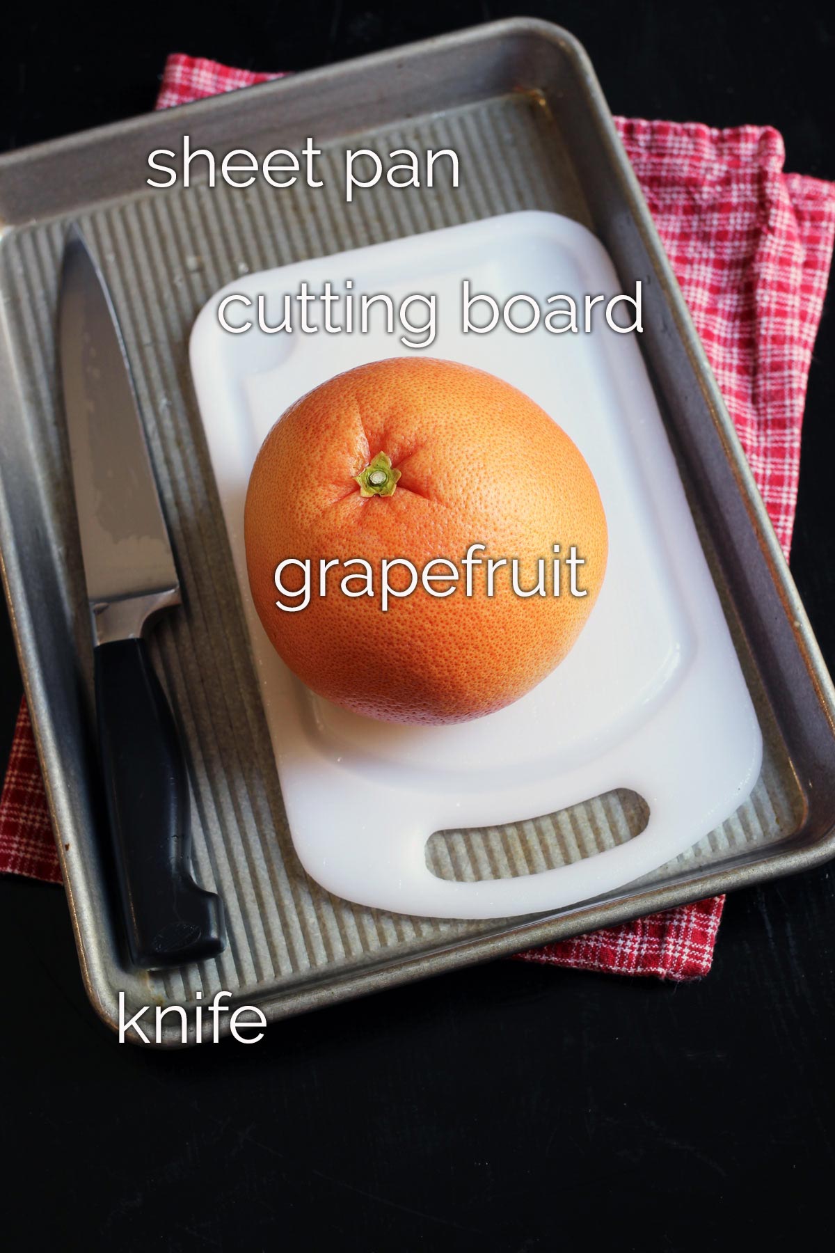 grapefruit on cutting board in sheet pan next to knife.