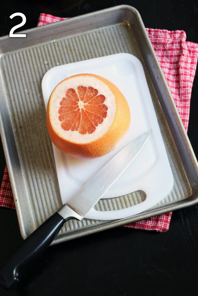 grapefruit standing on the cutting board with ends cut off.