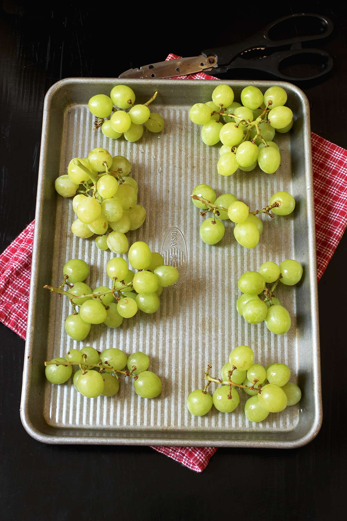 grape clusters laid out on small sheet pan atop a red cloth.